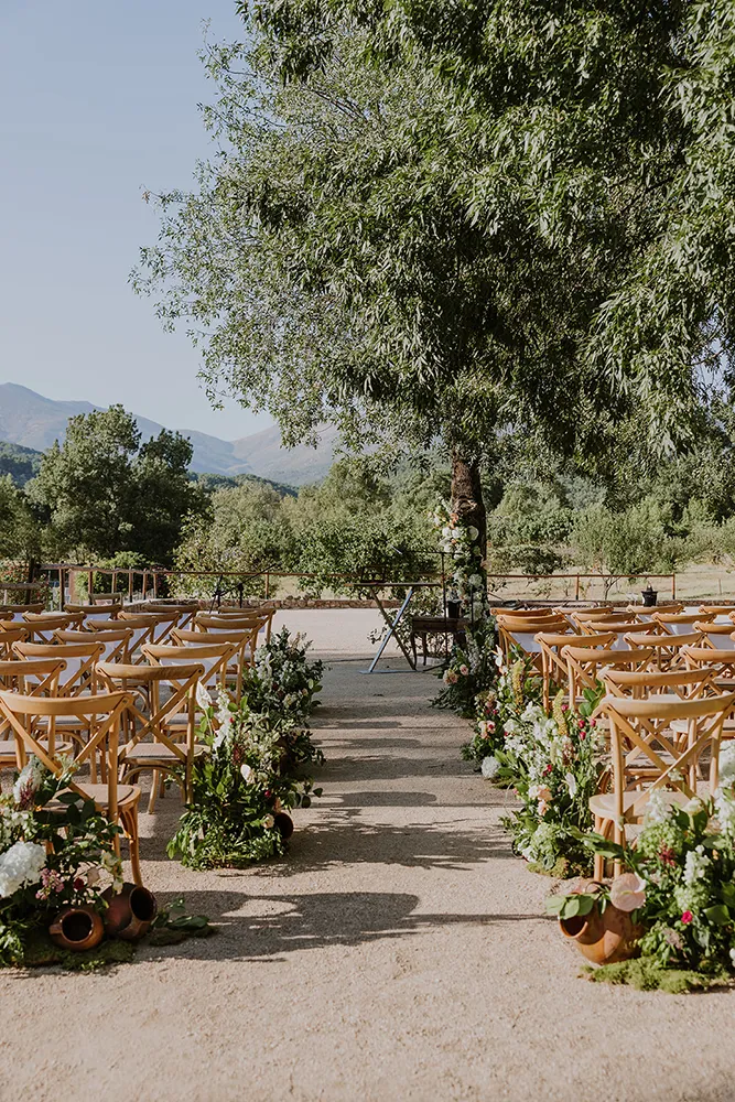 Detalle del espacio de ceremonia de Huellas del Tiétar preparado para una boda: sillas, flores, vista a la sierra. Lanzahíta
