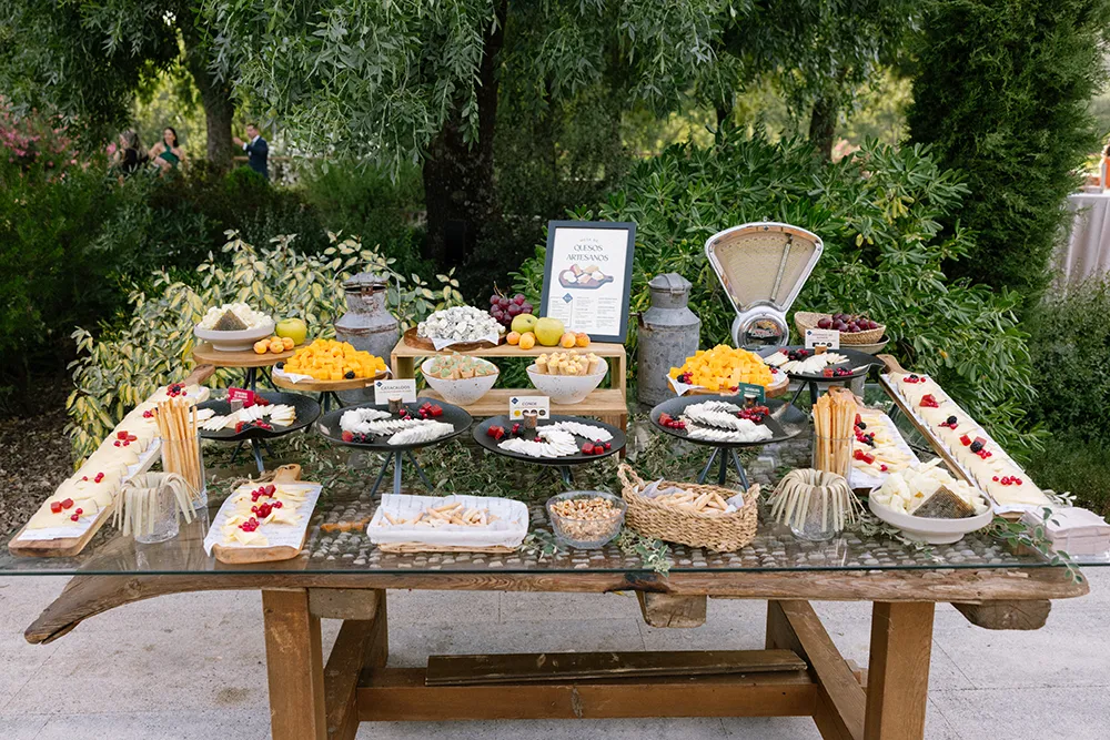 Cóctel de boda bajo los árboles en Huellas del Tiétar: mesa de quesos artesanos, estaciones de comida. Lanzahíta, Ávila