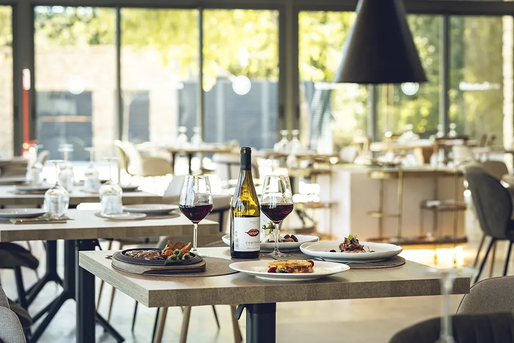 Mesa en el restaurante de Huellas del Tiétar preparada para servicio: productos de temporada, vinos del valle, luz de otoño. Lanzahíta, Ávila
